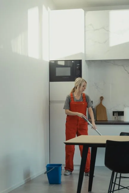gallery-1 Female crop in a purple sweatshirt and latex gloves cleaning a mirror in a bright apartment during the day